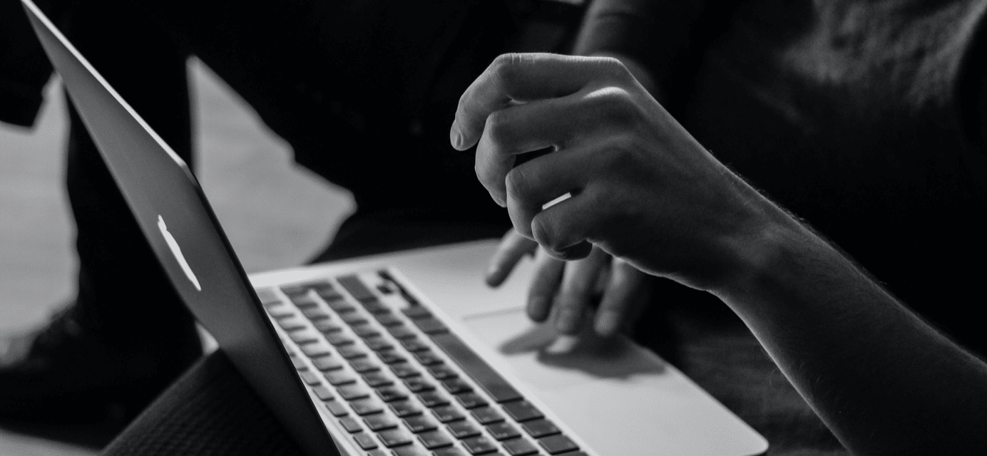 Black and white image of person working on laptop.